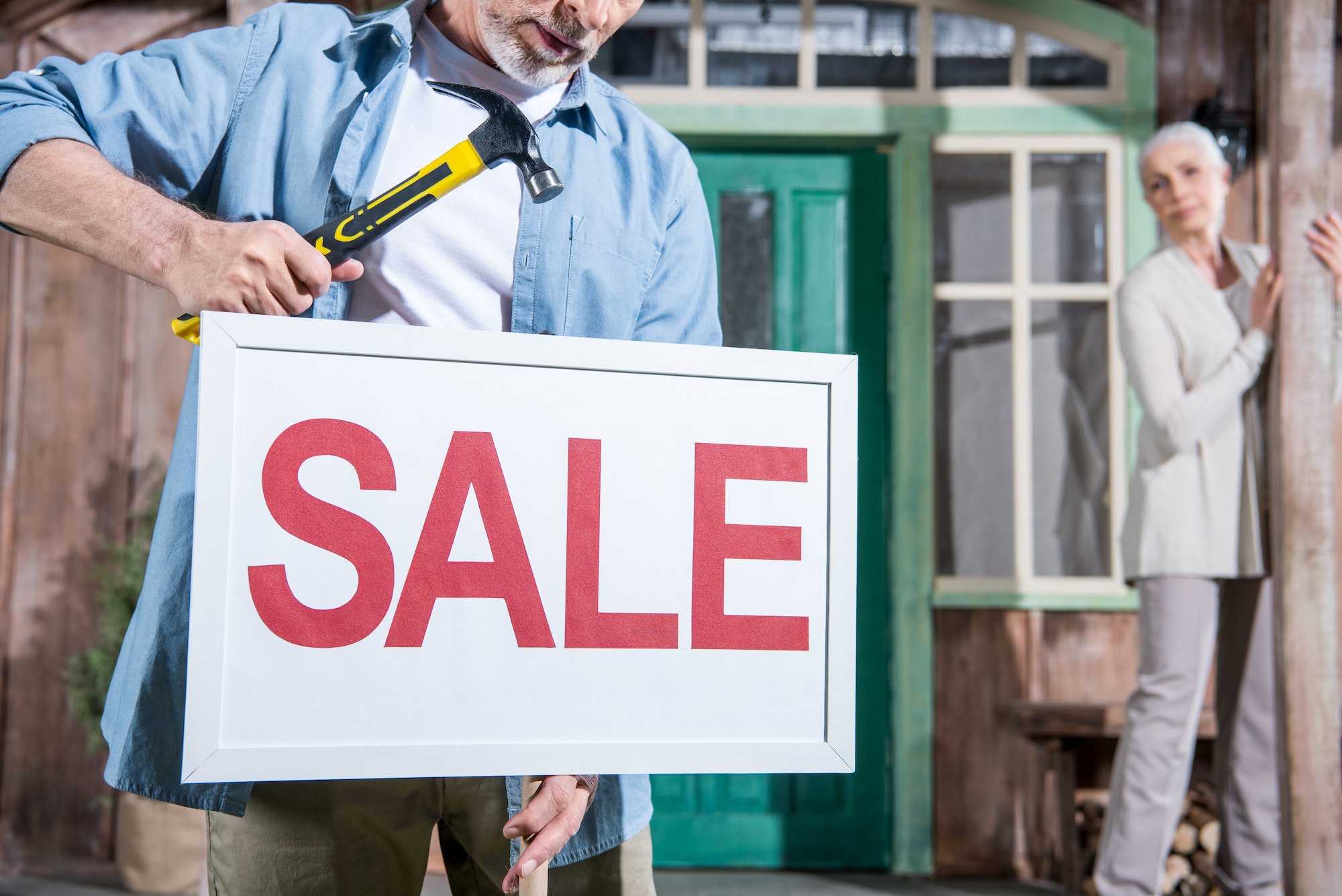 close up of sale sign, senior couple selling their house