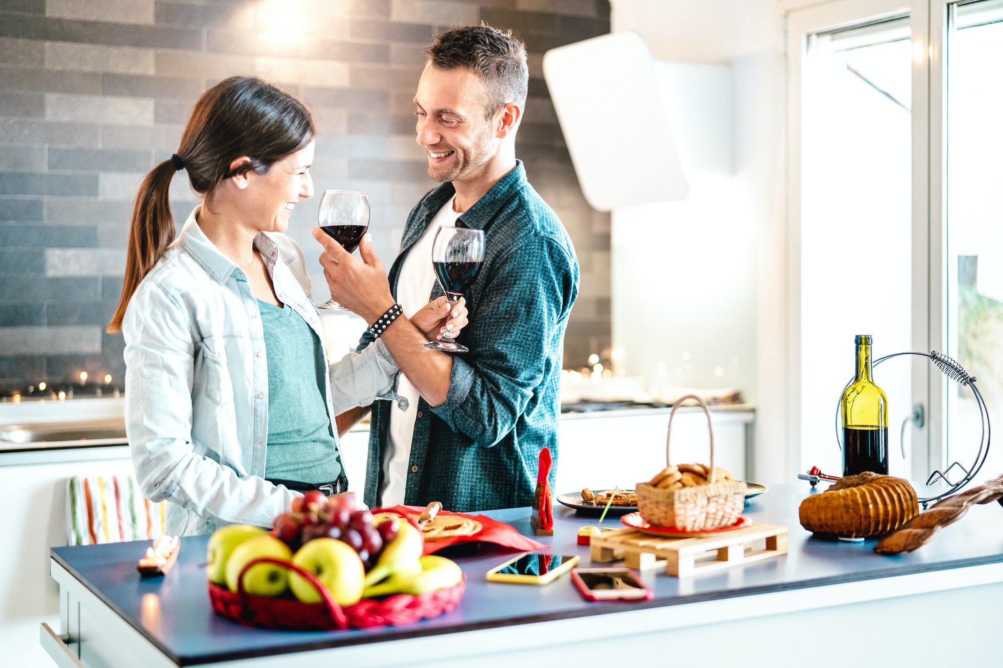 Young couple of lovers toasting red wine at house kitchen